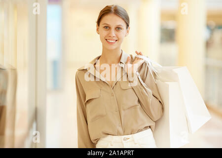Portrait der junge Schöne elegante Frau mit Einkaufstüten lächelnd in die Kamera während im Einkaufszentrum stehend Stockfoto
