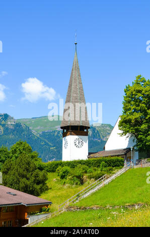 Schönen Evangelischen Kirche in Wengen, Schweiz fotografiert im Sommer mit grüne Landschaft. Die Berge im Hintergrund. Alpine Landschaft, Schweizer Alpen. Vertikale Fotografie. Stockfoto