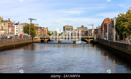 Blick nach Osten auf den Fluss Liffey an der Grattan Brücke mit Baukräne in den Himmel von Dublin, Irland, an einem sonnigen Sommertag Stockfoto