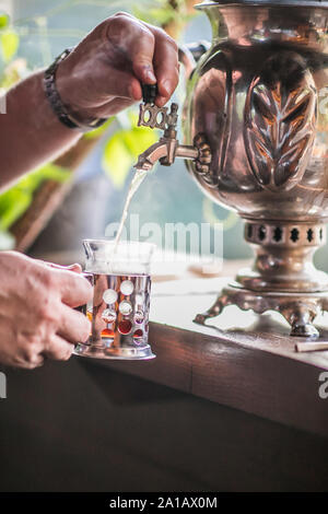 Der Mann ist das Gießen von Wasser aus der traditionellen alten russischen Samowar. Tea Time. Stockfoto