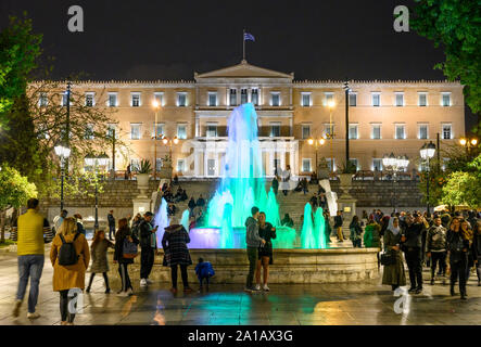 Menschenmassen genießen Sie am Abend einen Spaziergang am Syntagma Platz mit der Vouli, das Griechische Parlament Gebäude, im Hintergrund, zentral in Athen, Griechenland. Stockfoto