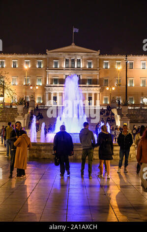 Menschenmassen genießen Sie am Abend einen Spaziergang am Syntagma Platz mit der Vouli, das Griechische Parlament Gebäude, im Hintergrund, zentral in Athen, Griechenland. Stockfoto
