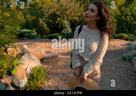 Frau in romantischen Kleidung und Strohhut Entspannung im Freien im Herbst oder Sommer Park und gutes Wetter zu genießen und den Sonnenuntergang. Schöne Natur Stockfoto
