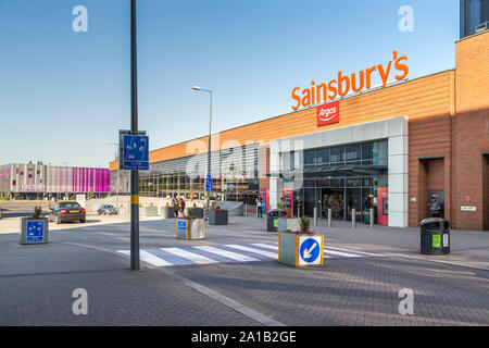 Das Stadtzentrum von Longbridge wird von Sainsbury's Superstore dominiert. Am Ende der Straße ist das Zentrum für junge Menschen in der Fabrik zu sehen. Stockfoto