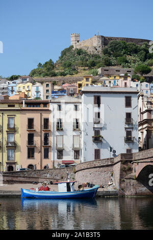 Angeln Boot günstig in der Nähe einer Brücke über den Fluss Temo in der Stadt Bosa im Norden Sardiniens. Die alten und bunten Stadt Gebäude, eine Kirche, ein Stockfoto