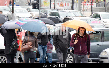 Belgrad, Serbien - September 24, 2018: die Menschen unter Regenschirmen Überqueren der Straße in der rush hour mit vielen Autos im Stau an einem regnerischen Tag in der Stadt Stockfoto