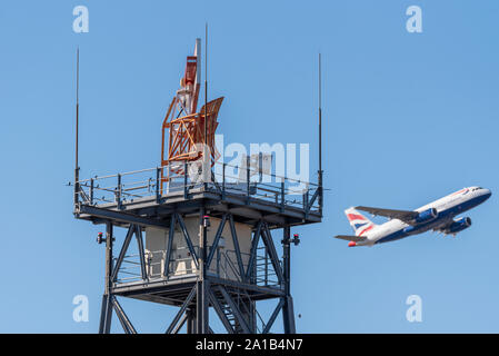 Eine Radarantenne am Flughafen London Heathrow in Betrieb. Kontrollierter Luftraum. British Airways Flugzeug startet. Vögel auf Struktur Stockfoto