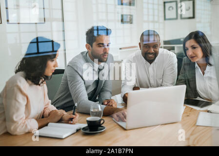 Diverse Kollegen arbeiten mit einem Notebook in einem Büro Stockfoto