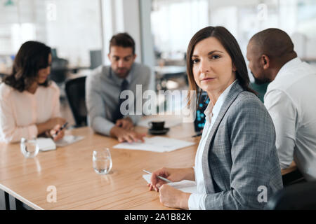 Fokussierte Geschäftsfrau, Sitzen mit Kollegen während einer Konferenz Stockfoto