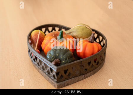 Verschiedene Sorten von dekorativen künstliche Kürbisse in einem wicker Schüssel auf der Zähler eine hölzerne Bauer. Gemüse Erntedank, Herbst Urlaub Hallow Stockfoto