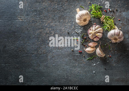 Knoblauchzehen und Zwiebel mit frischem Rosmarin Salz und Gewürz auf konkrete Tabelle Stockfoto
