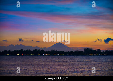 Gili Trawangan als im Hintergrund, Bali, Indonesien von Gili Meno mit Mount Agung nach Sonnenuntergang gesehen. Stockfoto