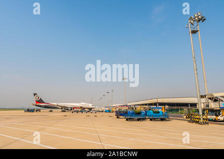 In Nanjing Lukou Flughafen Blick auf SF Airlines Flugzeug und Gepäckwagen für Fracht und Handling auf einem sonnigen blauen Himmel Tag Stockfoto