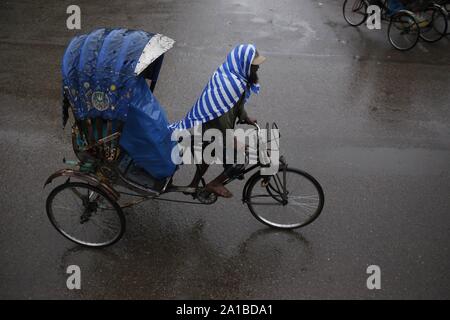 Dhaka, Bangladesch. 26 Sep, 2019. Eine Rikscha Abzieher und Passagiere nutzen Kunststoffplatten aus Regen in der Dhaka University Area zu speichern. Das tägliche Leben in der Region hat wegen starker Regenfälle unterbrochen. Credit: MD Mehedi Hasan/ZUMA Draht/Alamy leben Nachrichten Stockfoto