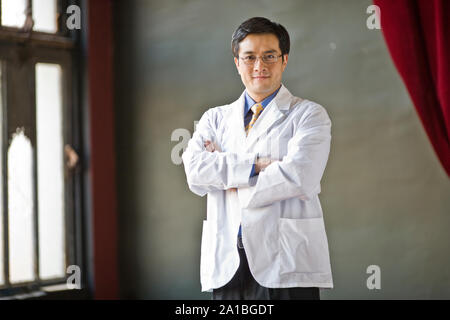 Porträt einer zuversichtlich männlicher Arzt Stehen mit verschränkten Armen. Stockfoto