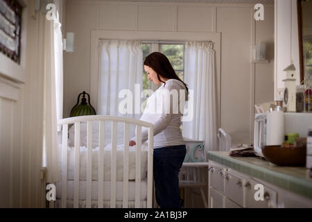 Seitenansicht einer schwangeren Frau, die eine Wiege. Stockfoto