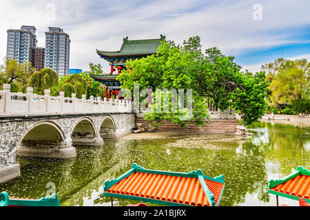 Urumqi Renmin Gongyuan People's Park atemberaubenden See Pavillon mit Wolkenkratzern im Hintergrund auf einem sonnigen blauen Himmel Tag Stockfoto