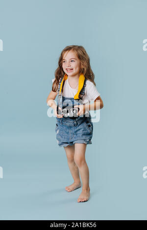 Glückliche kleine Mädchen, dass eine Vintage gespiegelt Kamera über blauen Hintergrund. Stockfoto