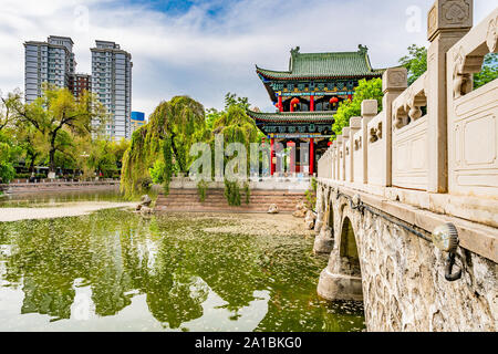 Urumqi Renmin Gongyuan People's Park atemberaubenden See Pavillon mit Wolkenkratzern im Hintergrund auf einem sonnigen blauen Himmel Tag Stockfoto