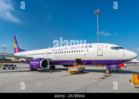 Besetzt das Bodenpersonal der Arbeitnehmer sind das Laden und Vorbereiten für den nächsten Flug ein urumqi Air Flugzeuge auf einem malerischen Sonnigen Tag Stockfoto