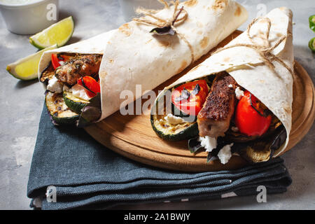 Wrap Sandwich mit gegrilltem Gemüse und Fleisch auf grauem Beton Hintergrund. Stockfoto