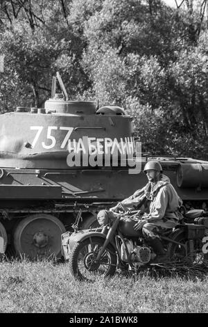 Sowjetischer Panzer T-34, Militärmotorrad und sowjetischer Soldat während des militärischen historischen Wiederaufbaus von "Karpaty 1944" in Medzilaborce, Slowakei. Stockfoto