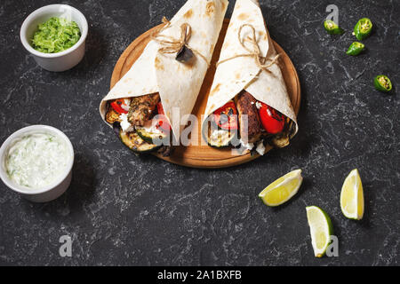 Wrap Sandwich mit gegrilltem Gemüse und Fleisch auf schwarzer Stein. Stockfoto