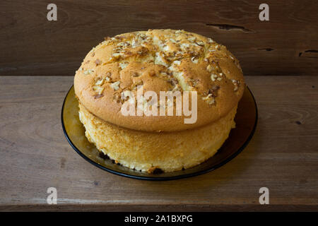 Baumwollschwammkuchen mit Walnüssen oben und Rosinen (getrocknete schwarze Trauben) unten, verzehrfertig, auf rustikalem Holztisch, hausgemacht Stockfoto