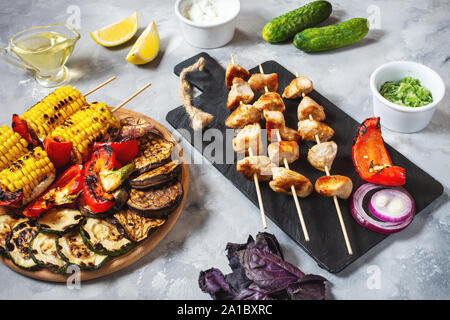 Verschiedene köstliche gegrillte Gemüse und Huhn kebab am Spieß auf einen konkreten Hintergrund. Sommer essen Grill. Stockfoto
