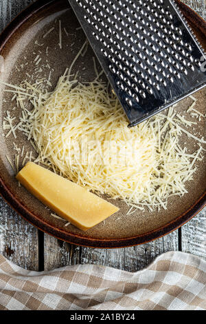 Leckere geriebener Käse. Parmesan auf Platte und reibe. Ansicht von oben. Stockfoto