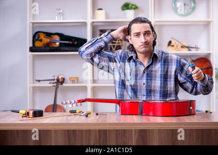 Die junge schöne Handwerker Reparatur Gitarre Stockfoto
