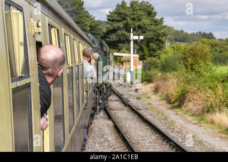 GLOUCESTERSHIRE, ENGLAND - September 2019: Rail Enthusiasten aus dem Fenster eines Zuges auf der Gloucestershire und Warwickshire Railway lehnend. Stockfoto