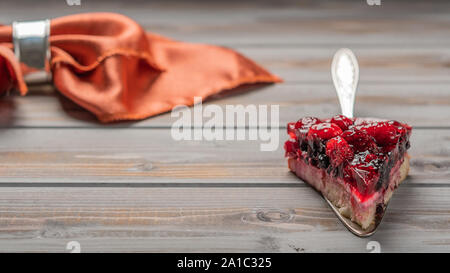 Stück Kuchen mit Beeren: Himbeere, Johannisbeere, Erdbeere auf ein Metall Spachtel auf Holz Hintergrund, , Serviette Stockfoto