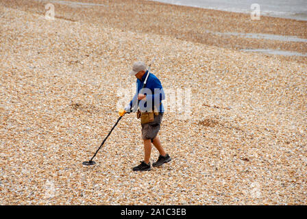 Mann Kundenakquise mit einem Metalldetektor am Strand von Lyme Regis, Dorset, England Stockfoto