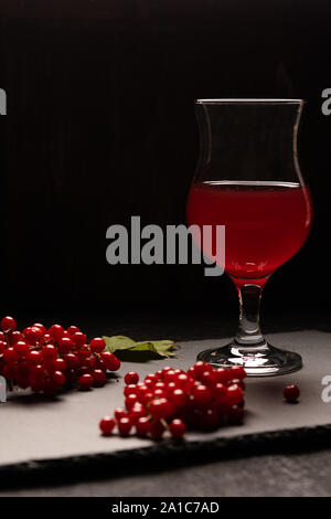 Den roten Saft der viburnum mit einem stammte aus Glas auf einem schwarzen Hintergrund. In der Nähe von viburnum Beeren. Gesunde Ernährung Stockfoto