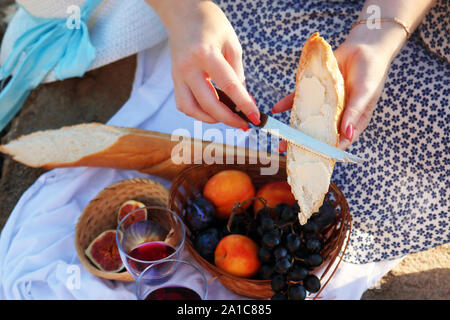 Weibliche Hände bestreichen Butter auf ein Stück Brot Stockfoto