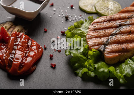 Hausgemachte gegrilltes Lachssteak auf Salatblättern. Neben gebackenes Gemüse, Sojasauce, Kalk. Gesunde Ernährung Stockfoto