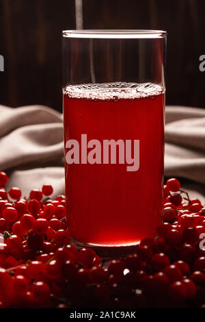 Rote Saft von viburnum in einem Glas auf einem dunklen Hintergrund. In der Nähe von viburnum Beeren, und Leinen. Gesunde Ernährung Stockfoto