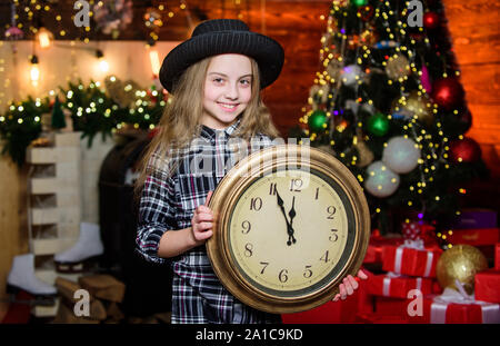 Girl santa claus hat und die Uhr. Weihnachten Treffen Urlaub. Festliche Atmosphäre Weihnachten. Silvester Countdown. Die Zählung der Zeit. Weihnachten fast hier. Nur wenige Minuten bis zum neuen Jahr. Beeilen Sie sich wünschen. Stockfoto