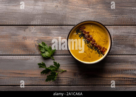 Hausgemachte Cremesuppe mit einer Mischung aus Bohnen mit rotem Pfeffer, Petersilie und schwarzem Sesam auf einer hölzernen Hintergrund. Ansicht von oben Stockfoto