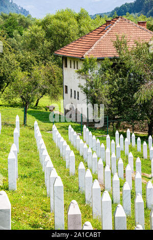 Potocari, Bosnien und Herzegowina - Juli 31., 2019. Grabsteine mit Haus demaged während des Krieges im Hintergrund Stockfoto