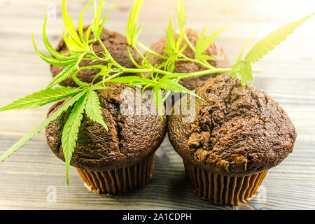 Schokolade Cannabis cupcake Muffins und Hanf Blätter auf hölzernen Tisch Stockfoto