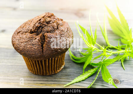 Schokolade Cannabis cupcake Muffin und Hanf Blätter auf hölzernen Tisch Stockfoto