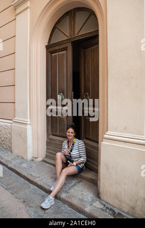 Bonifacio, Corsica-September, 2019. Europäische Frau Touristen sitzen auf dem Schritt in der Nähe der Tür des Hauses Stockfoto