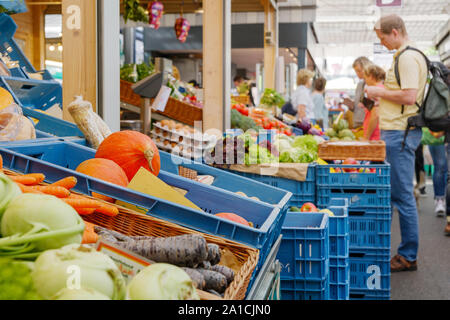 Gemüse verkaufen auf Reihe von Kunststoff blau Warenkorb vor außerhalb Lebensmittelgeschäft neben Flur der Open-Air-Markt mit Hintergrund der Kunden ausgeht. Stockfoto