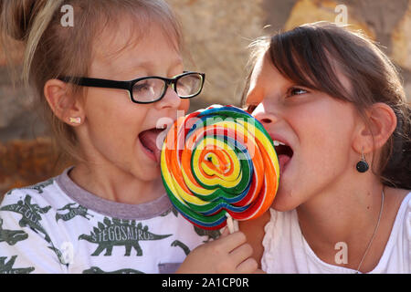 Zwei Schwestern teilen sich einen bunten Lutscher Stockfoto