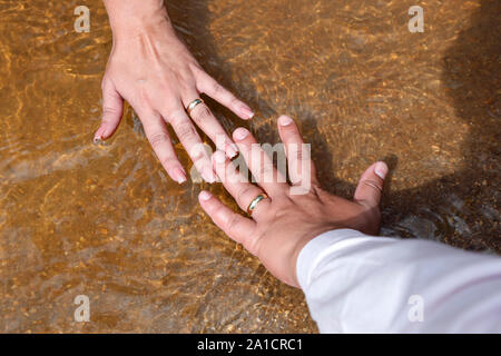 Pflegt Hände verbunden mit Hochzeit Ringe - Goldene Hochzeit Ringe Stockfoto