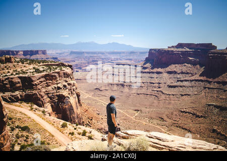 Mitte Alter kaukasischer Mann steht am Rand der Klippe unter den roten Felsen der Schlucht Stockfoto