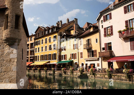 Geschäfte und Restaurants auf dem Quai de l'Ile von der anderen Seite des Kanals Le Thiou neben dem Palais de l'Ile in der Altstadt von Annecy, Frankreich. Stockfoto