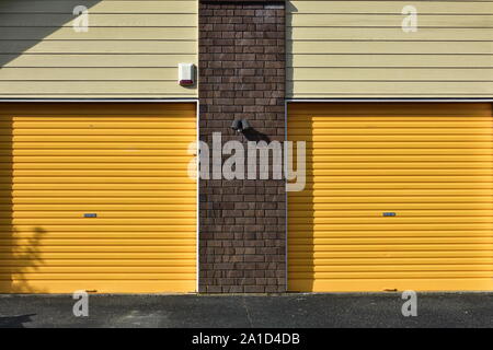 Gelbe Metall garage Tore mit Mauer zwischen Ihnen und vor weatherboard Verkleidungen. Stockfoto